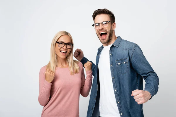 Excited couple in eyeglasses showing yeah gesture isolated on grey — Stock Photo