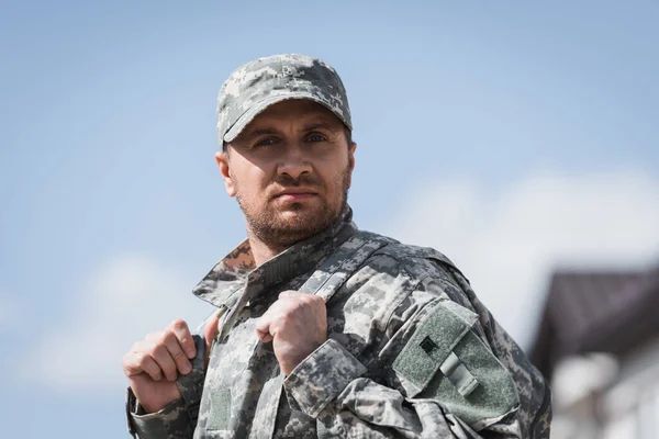 Fiducioso uomo militare adulto in uniforme guardando la fotocamera su sfondo sfocato — Foto stock