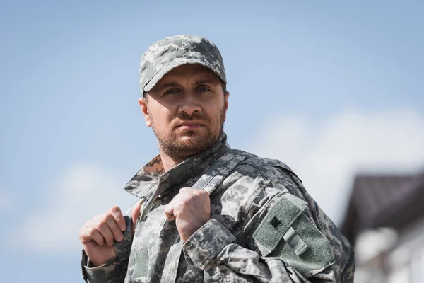 Confident adult military man in uniform looking at camera on blurred background — Stock Photo