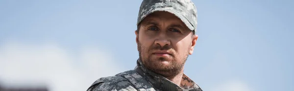 Uomo serio in uniforme militare che guarda la macchina fotografica su sfondo sfocato, banner — Foto stock