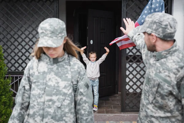 Daughter and father in camouflage waving each other near home — Stock Photo