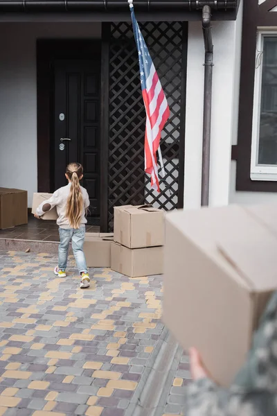 Маленькая девочка с картонной коробкой в дом на размытом переднем плане — стоковое фото