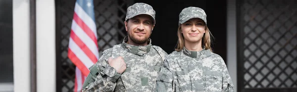 Smiling military couple looking at camera on blurred background, banner — Stock Photo