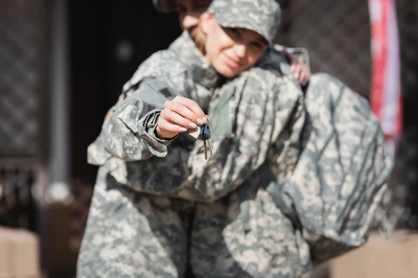 Chiavi con moglie militare offuscata e marito che si abbraccia sullo sfondo — Foto stock