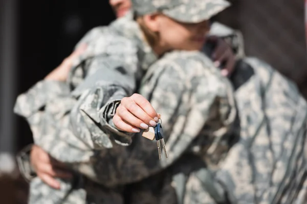 Keys with blurred military wife and husband embracing on background — Stock Photo