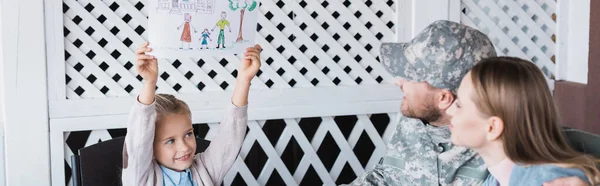 Happy girl showing picture with family near mother and father at home, banner — Stock Photo