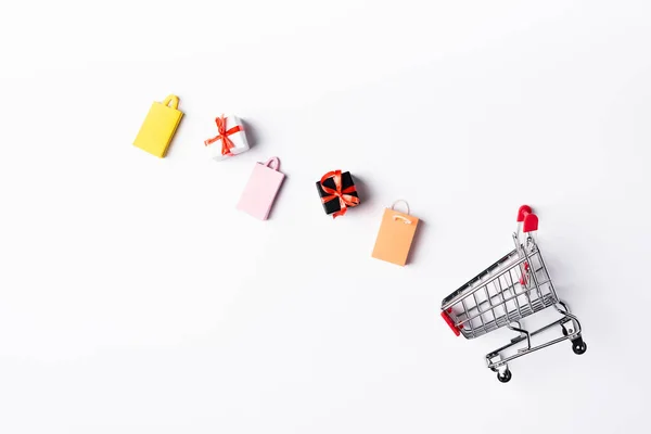 Draufsicht auf bunte Spielzeug-Einkaufstaschen und Geschenkboxen in Warenkorbnähe auf weißem Hintergrund — Stockfoto