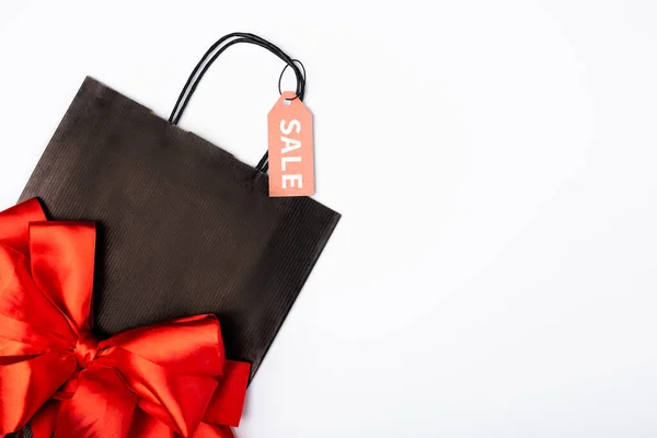 Vue du dessus du sac à provisions noir avec arc et étiquette de prix avec lettrage de vente sur fond blanc — Photo de stock