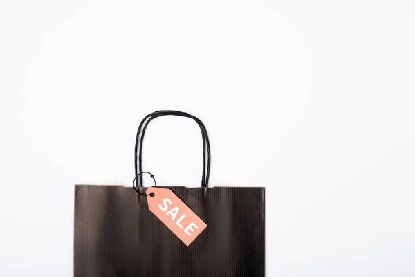 Top view of black shopping bag with sale lettering on price tag on white background — Stock Photo