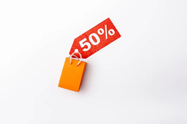 Top view of price tag with 50 percent signs and toy shopping bag on white background — Stock Photo