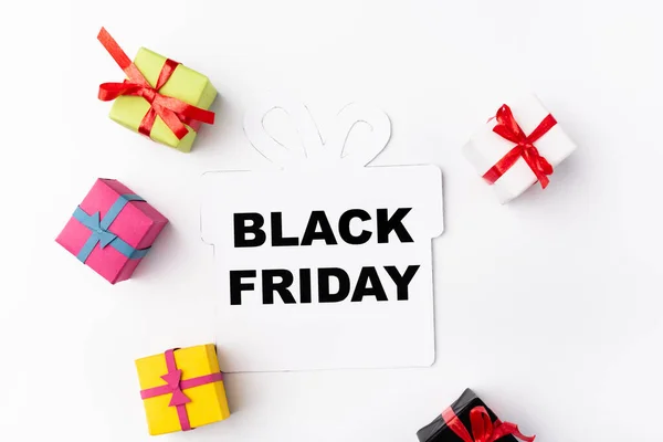 Draufsicht auf Papierelement mit schwarzem Freitag-Schriftzug in der Nähe von Spielzeug-Einkaufstaschen auf weißem Hintergrund — Stockfoto