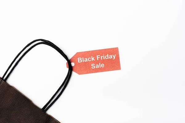 Top view of shopping bag and price tag with black friday sale lettering on white background — Stock Photo