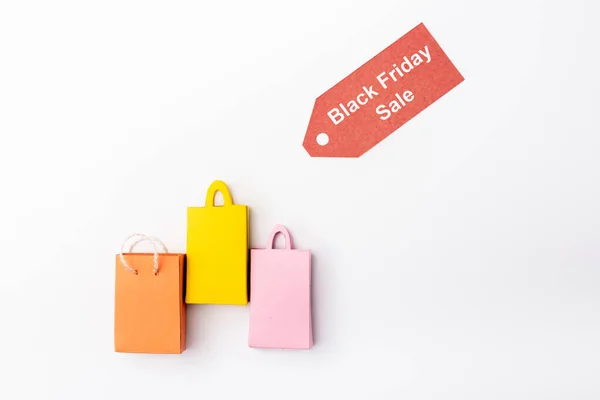 Top view of small shopping bags with red price tag with black friday sale lettering on white background — Stock Photo