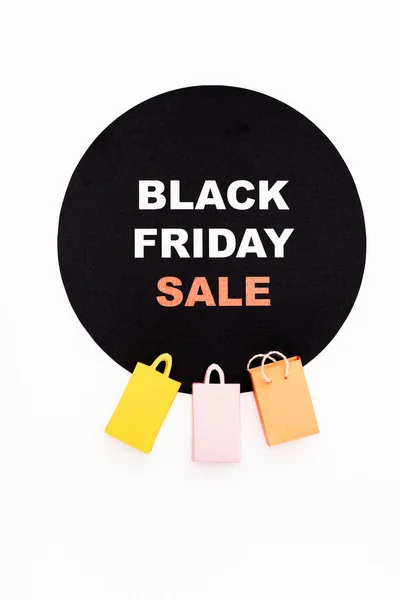 Top view of colorful toy shopping bags near black circle with black friday lettering on white background — Stock Photo