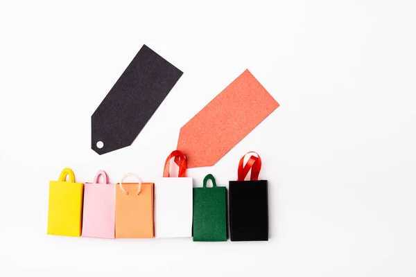 Top view of empty price tags near small shopping bags on white background — Stock Photo