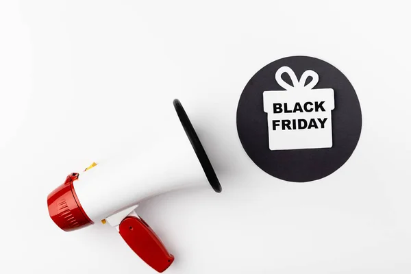 Top view of loudspeaker near black circle with paper gift box and black friday lettering on white background — Stock Photo