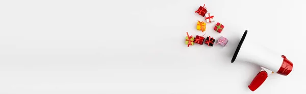 Panoramic shot of loudspeaker and toy gifts on white background — Stock Photo