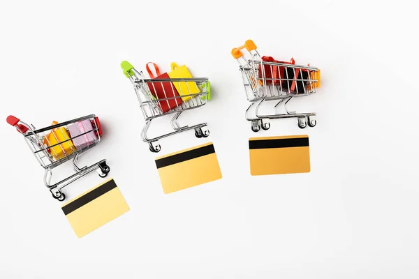 Vue du dessus des chariots de jouets avec des cadeaux et des cartes de crédit sur fond blanc — Photo de stock