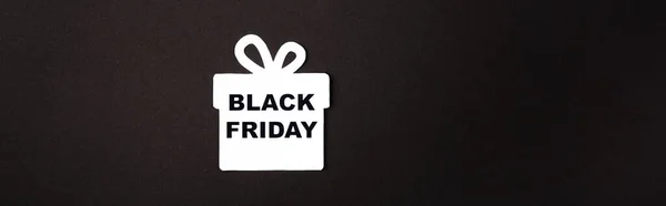 Panoramic shot of paper gift box with black friday lettering on black background — Stock Photo