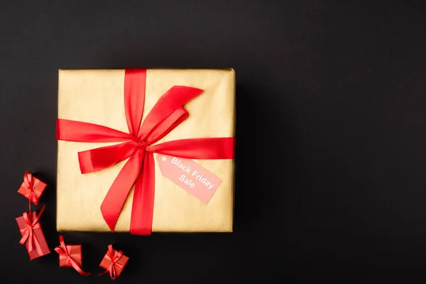 Vista dall'alto del regalo con cartellino del prezzo e venerdì nero in vendita su sfondo nero — Foto stock