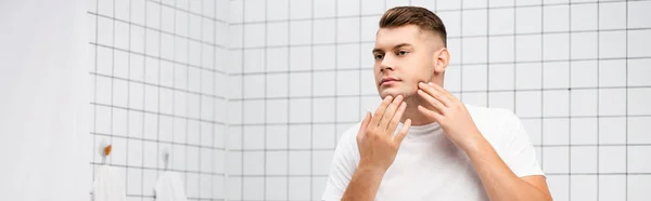 Young adult man touching face in bathroom, banner — Stock Photo