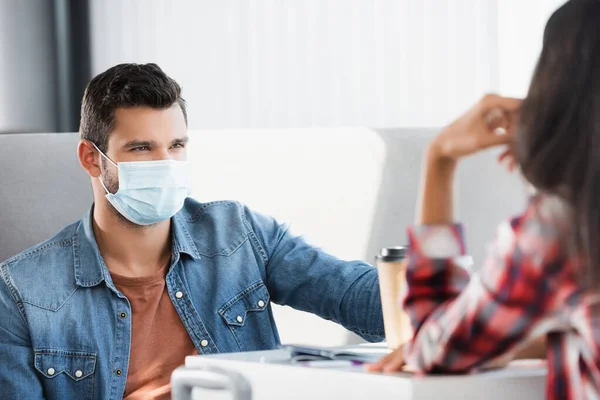 Man in medical mask looking at brunette woman in airport — Stock Photo