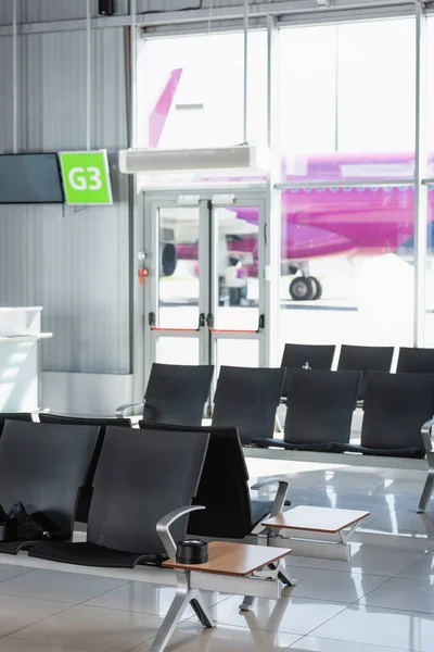 Черные сиденья в зале вылета в современном аэропорту — стоковое фото