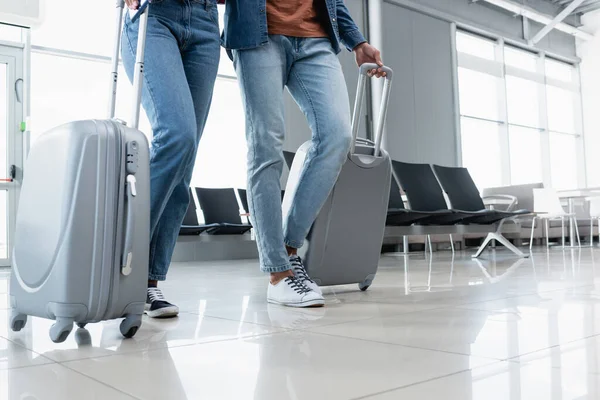 Vue partielle du couple marchant avec ses bagages à l'aéroport — Photo de stock