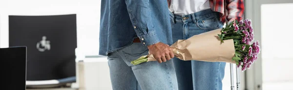Cropped view of man holding wrapped flowers while meeting girlfriend in airport, banner — Stock Photo