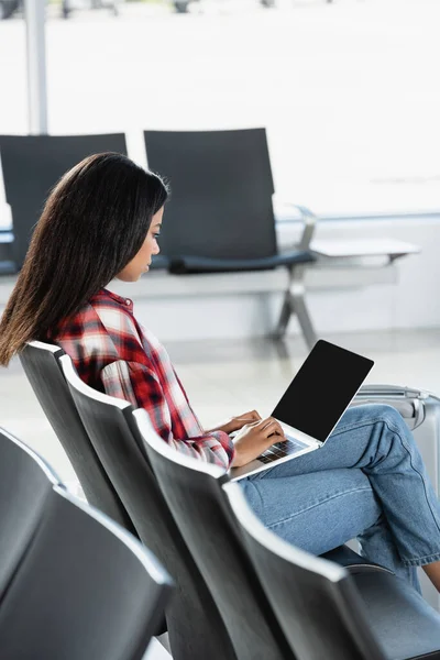 Brunette african american woman using laptop in departure lounge of airport — Stock Photo