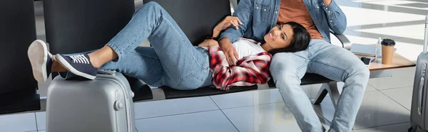 Mujer afroamericana feliz acostada cerca del hombre en la sala de salida, pancarta - foto de stock