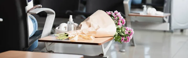 Wrapped bouquet of flowers on table near bottle with sanitizer and wireless headphones, banner — Stock Photo