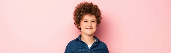 Panoramic crop of pleased and curly boy in denim shirt smiling on pink — Stock Photo