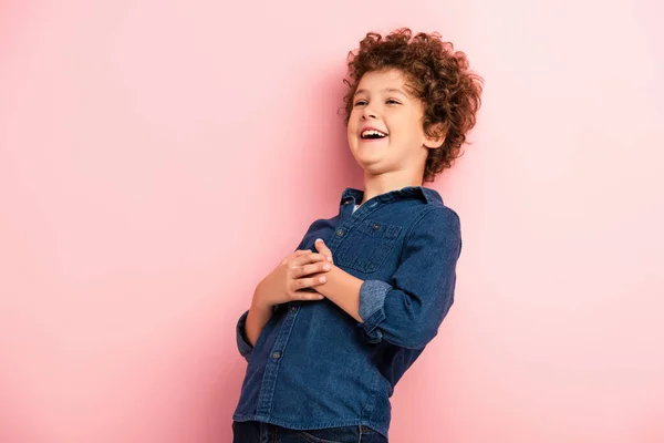 Menino alegre e encaracolado em camisa jeans rindo em rosa — Fotografia de Stock