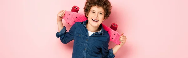 Website header of curly boy laughing and holding penny board on pink — Stock Photo