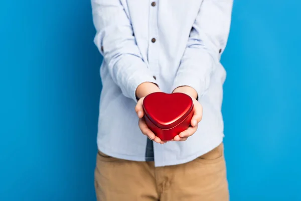 Recortado vista de niño sosteniendo rojo corazón forma caja en azul - foto de stock