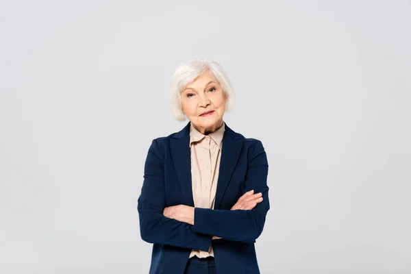 Elderly woman with crossed arms looking at camera isolated on grey — Stock Photo