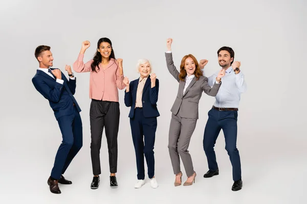 Fröhliche multiethnische Geschäftsleute zeigen Ja-Geste auf grauem Hintergrund — Stockfoto