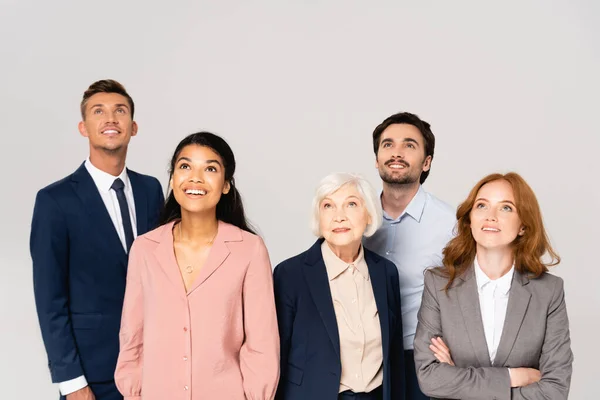 Smiling multicultural businesspeople looking up isolated on grey — Stock Photo