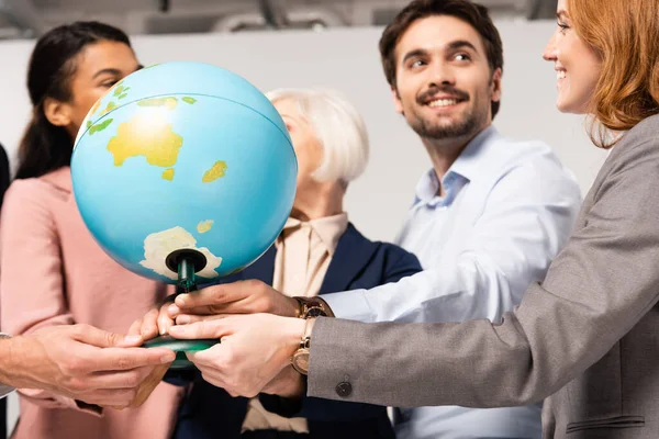 Глобус в руках усміхнених багатоетнічних бізнесменів на розмитому тлі — стокове фото