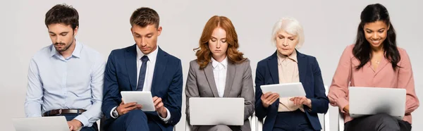 Multiethnische Geschäftsleute mit digitalen Tablets und Laptops isoliert auf grauem Banner — Stockfoto