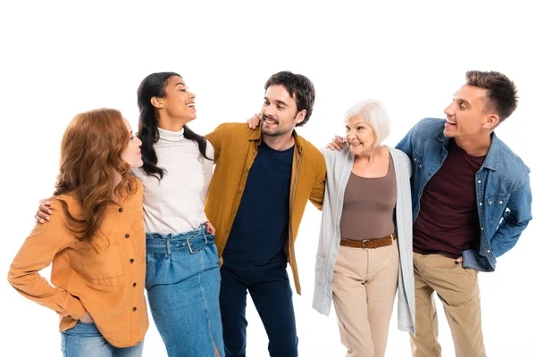 Sonriente gente multicultural mirándose mientras se abrazan aislados en blanco - foto de stock