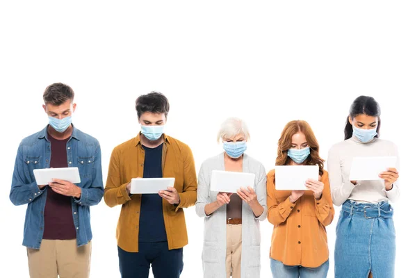 Мультиэтнические люди в медицинских масках с помощью цифровых таблеток изолированы на белом — стоковое фото