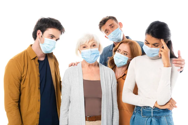 Sad multiethnic people in medical masks standing isolated on white — Stock Photo