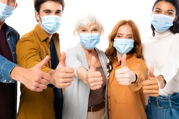 Pessoas multiétnicas mostrando como enquanto vestindo máscaras médicas em fundo borrado isolado em branco — Fotografia de Stock