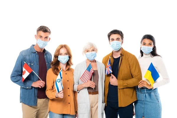 Multicultural people in medical masks holding flags and looking at camera isolated on white — Stock Photo