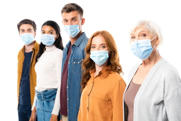 Femme en masque médical regardant la caméra près d'amis multiculturels sur fond flou isolé sur blanc — Photo de stock