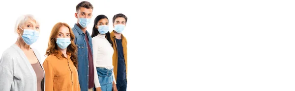 Молодые люди в медицинских масках, смотрящие в камеру рядом с многонациональными друзьями, изолированными на белом, баннер — стоковое фото