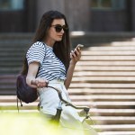 Vue latérale de jeune femme attrayante en utilisant un smartphone sur la rue