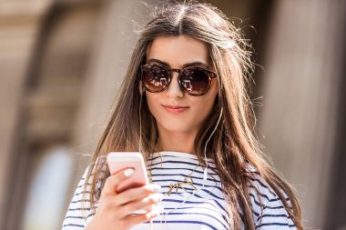 sokakta smartphone kullanarak güneş gözlüklü genç çekici kadın portresi